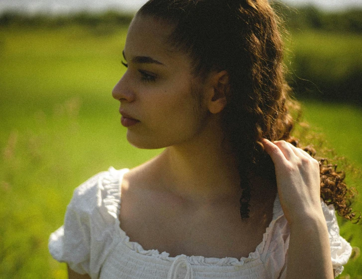 a close - up of a young woman standing in a grassy field