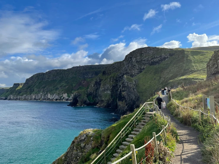 several people walking down a trail near the ocean