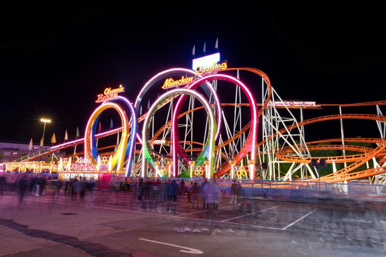 a carnival with a ferris wheel and roller coasters at night
