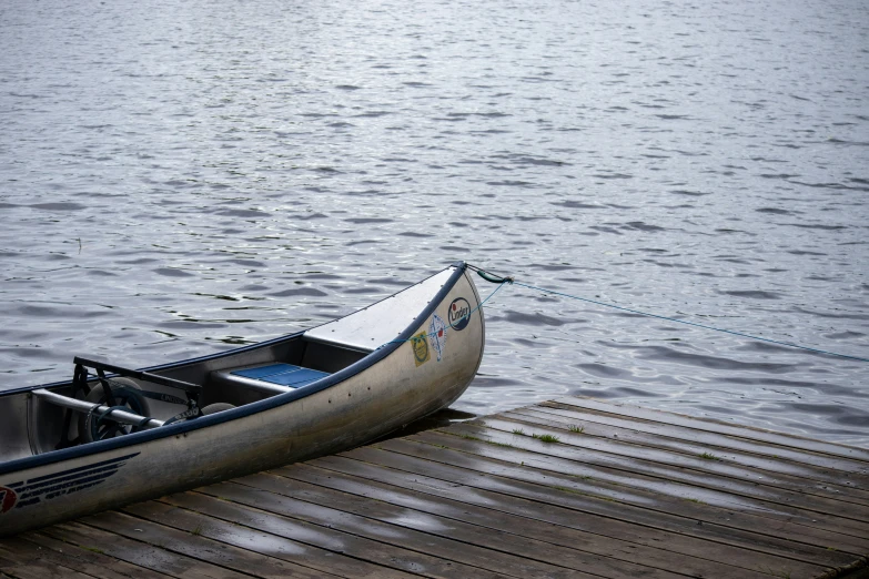 an empty canoe on a wooden dock in front of water