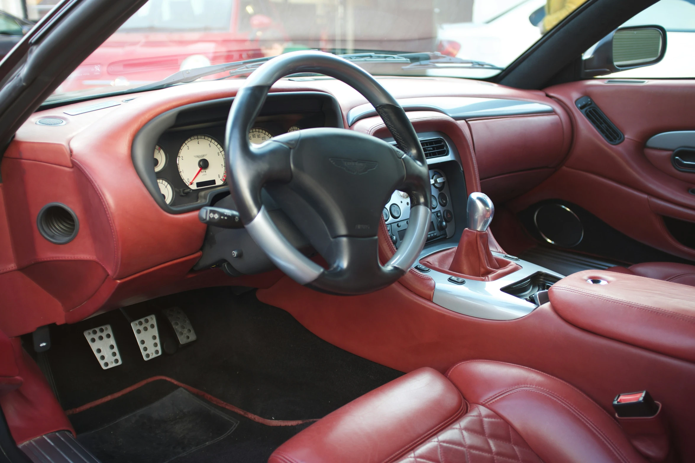 a red interior of a car with ons and steering controls
