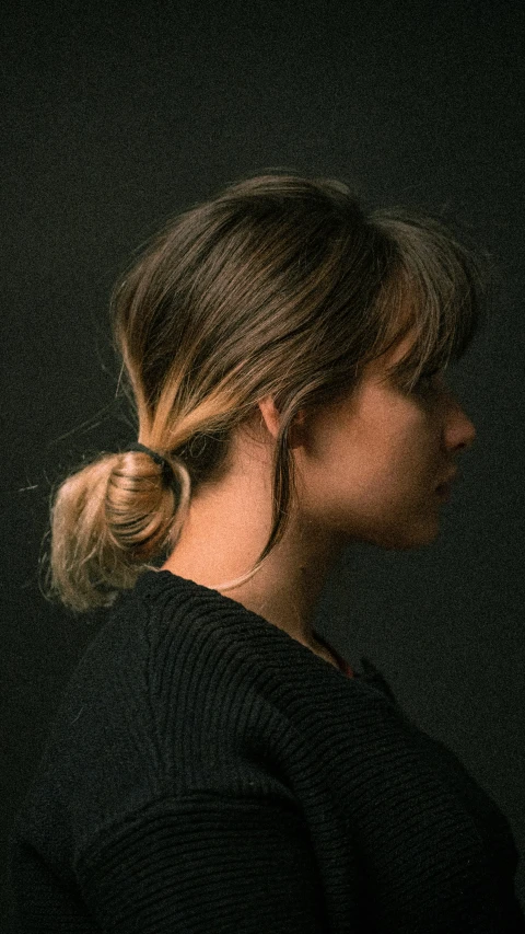 a woman with blonde hair and bun in the dark