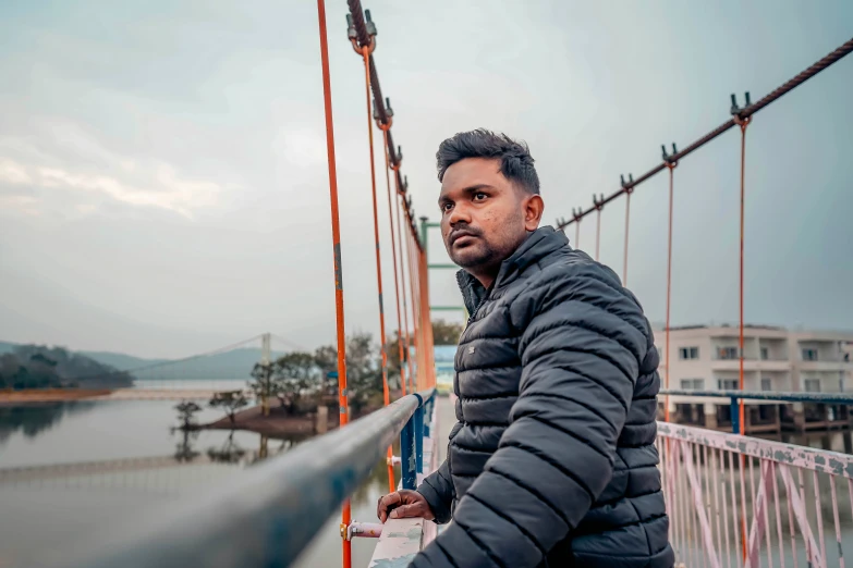 a man standing on the edge of a bridge next to water