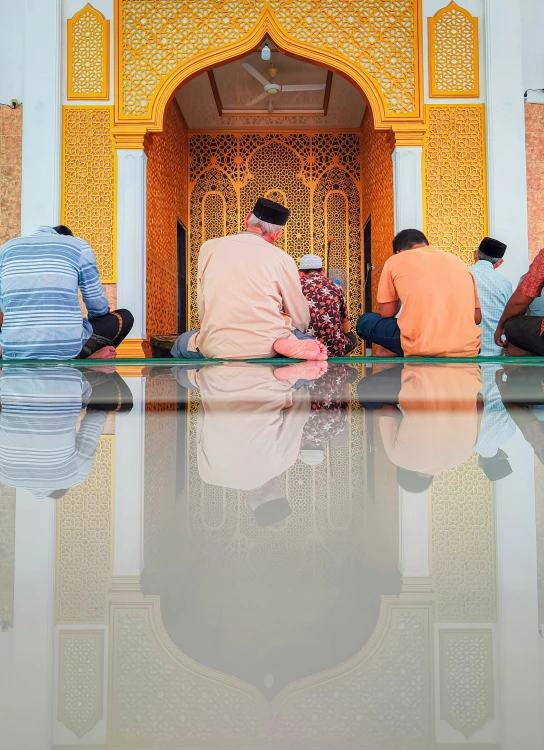 three men sit on the floor in front of an ornate building