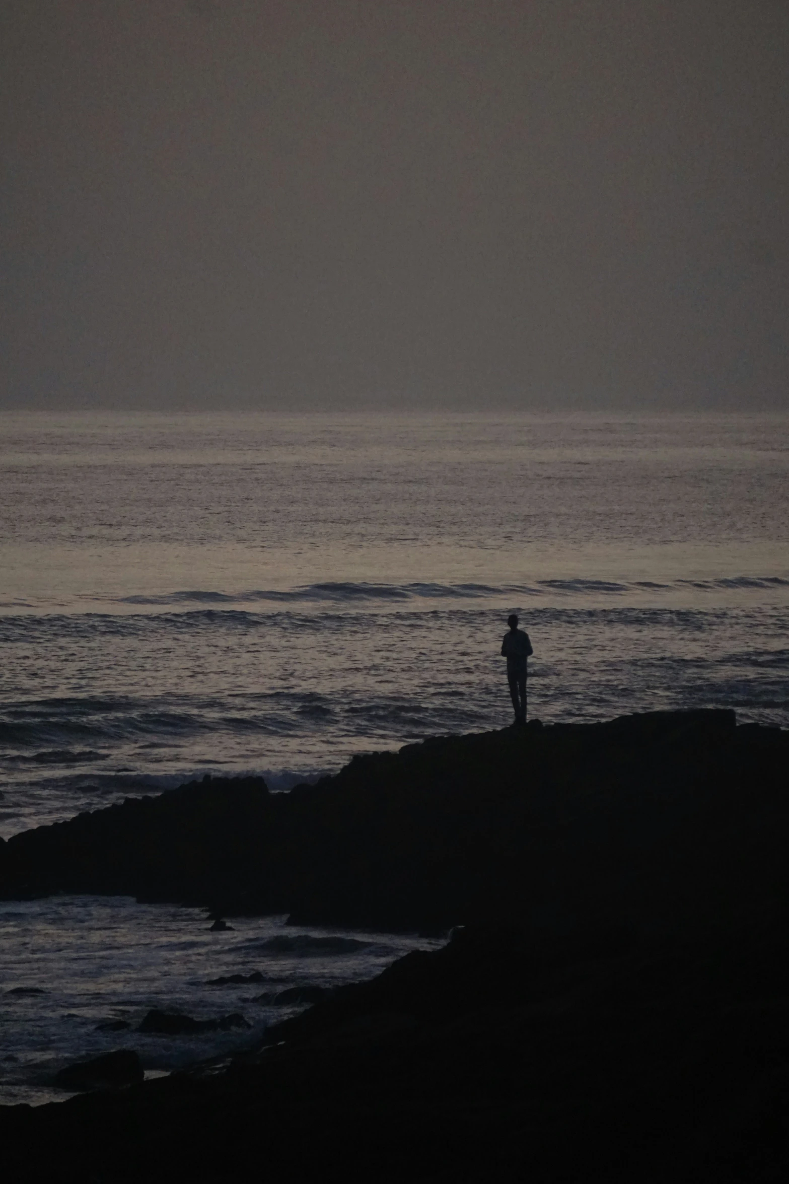 person standing in front of the water at dusk