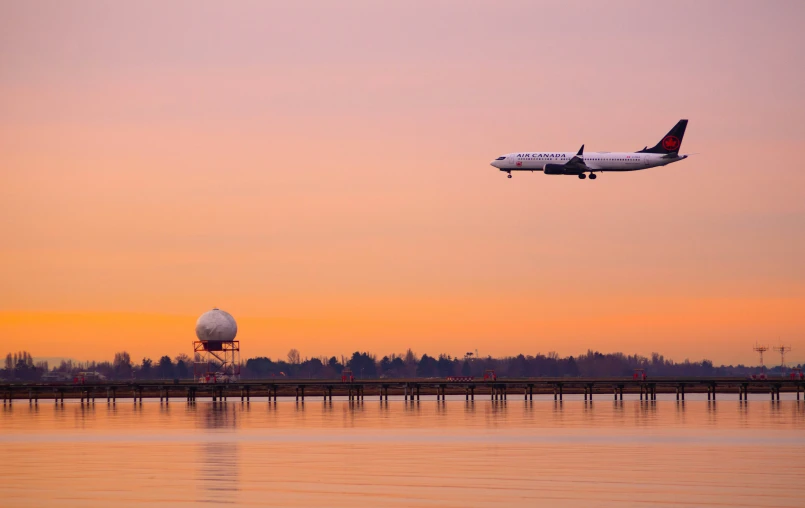 a jet airplane flying over the water and pier