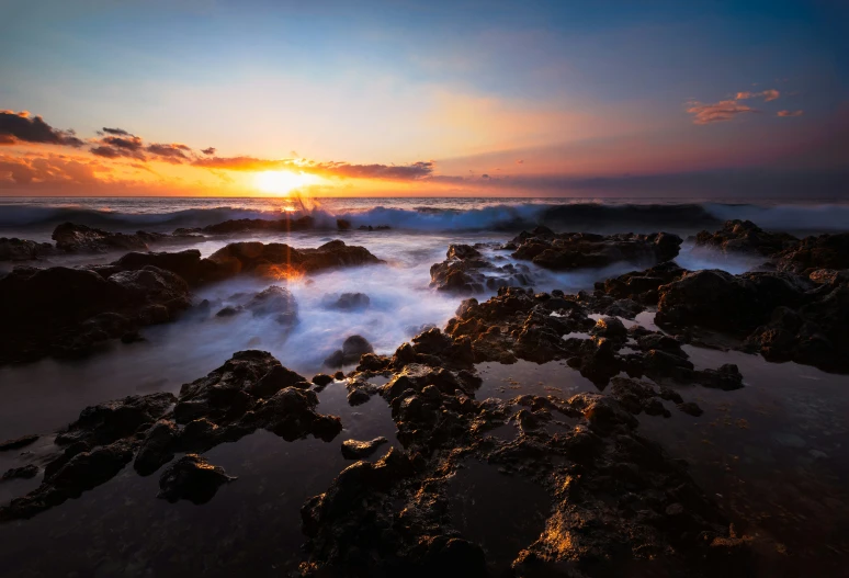 a sunset at the beach with small waves