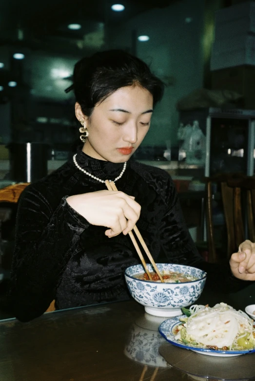 a woman wearing a black dress eating from a bowl