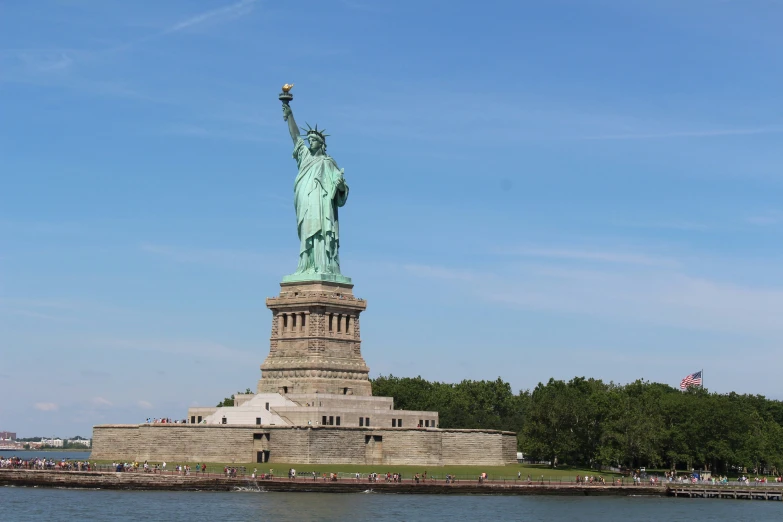 the statue of liberty stands on the edge of the river