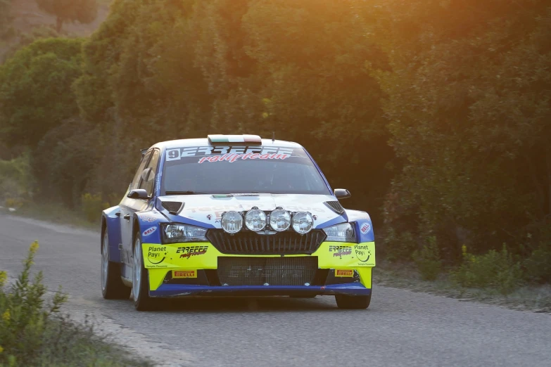 a blue and white car drives down a wooded road