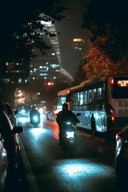 two city busses driving in the street in the dark