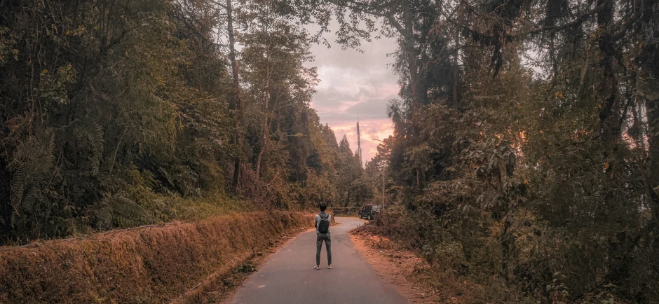 two people walking down the sidewalk in a wooded area