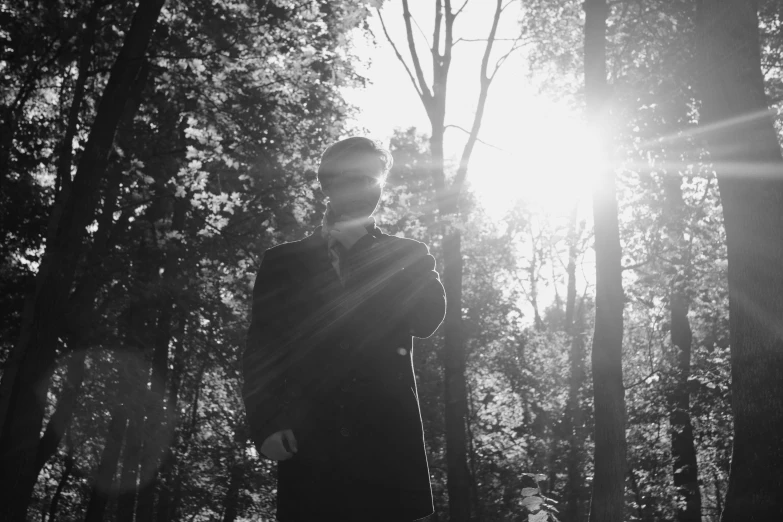 a man standing in the forest under a sun