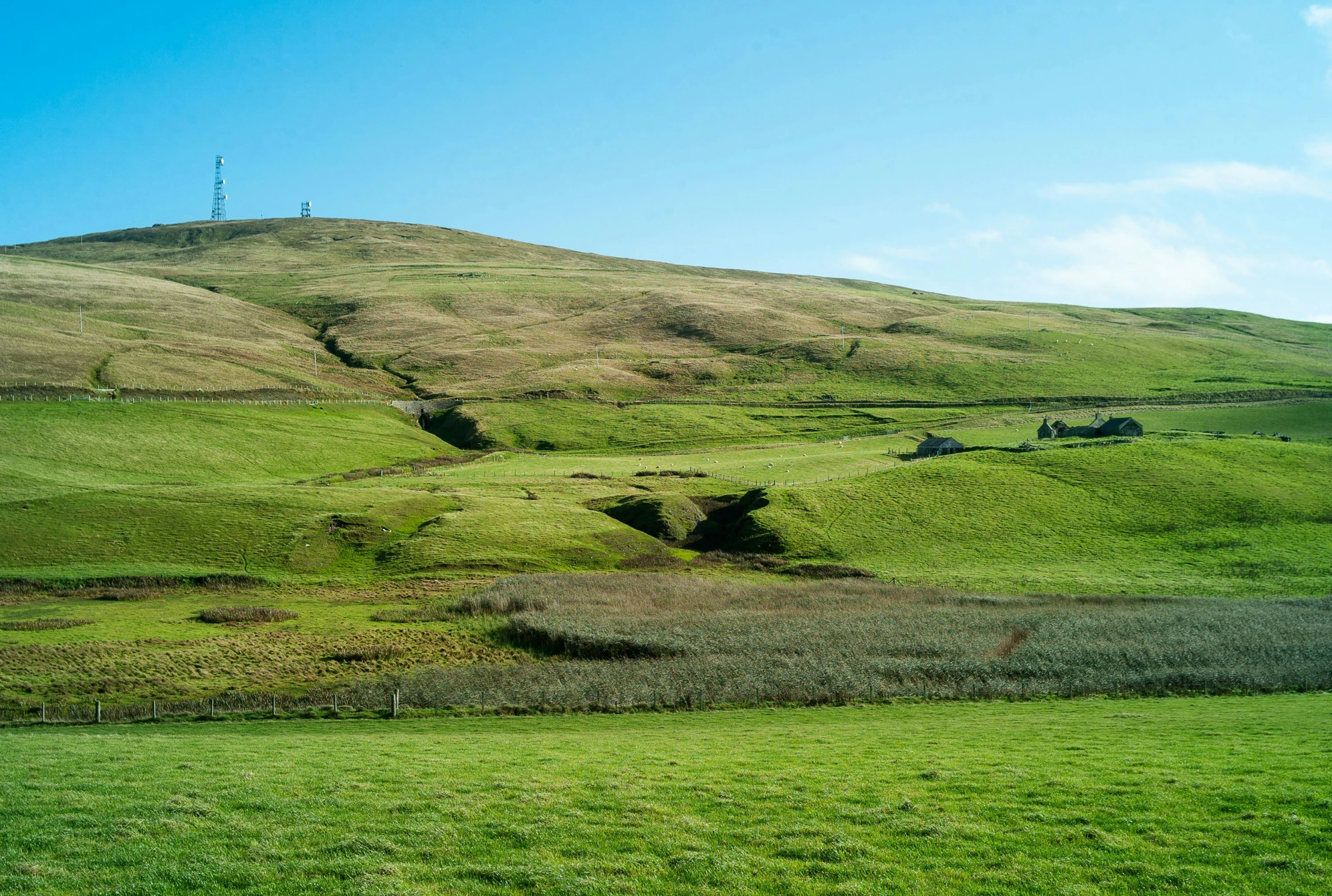 grassy terrain, with hills and a radio mast on top