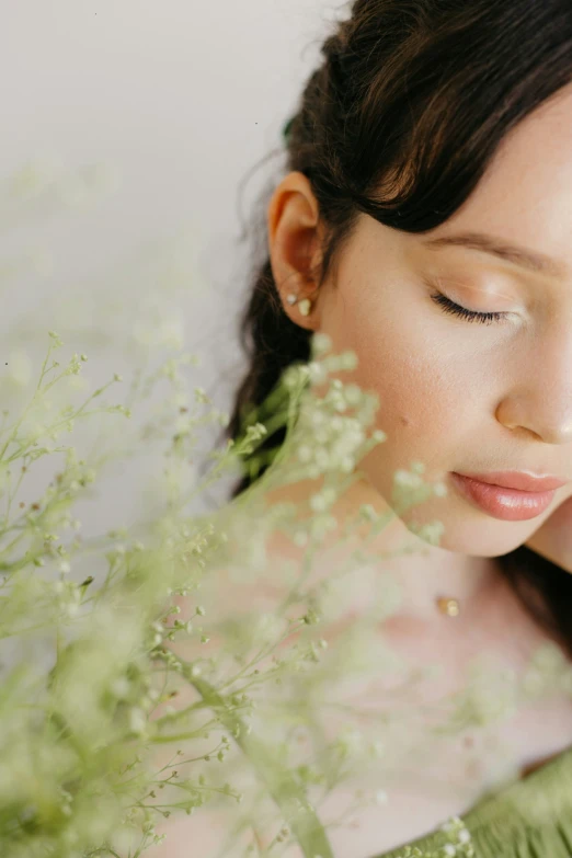 woman with eyes closed leaning on plant with flowers