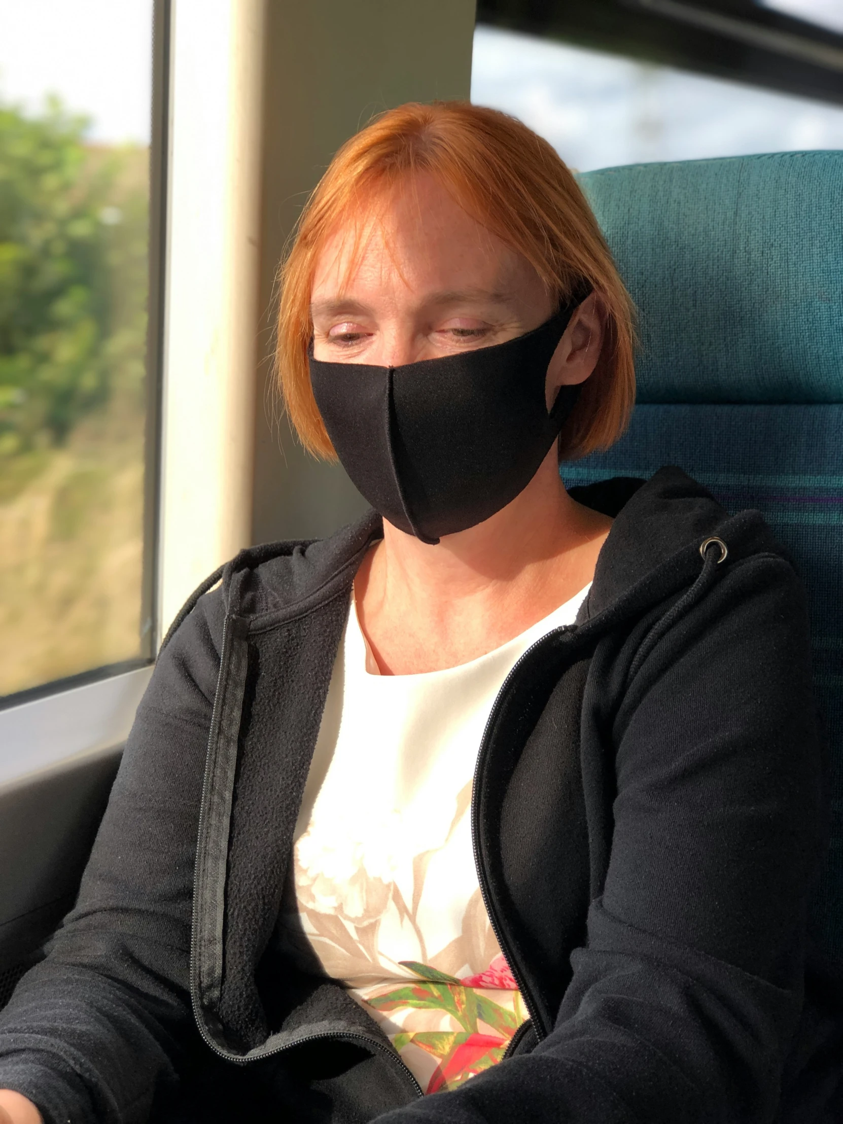 a woman in white shirt and black mask on a train