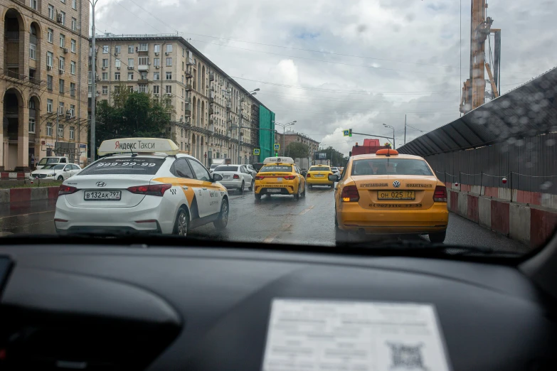 view of street with cars and taxi cabs from inside of vehicle