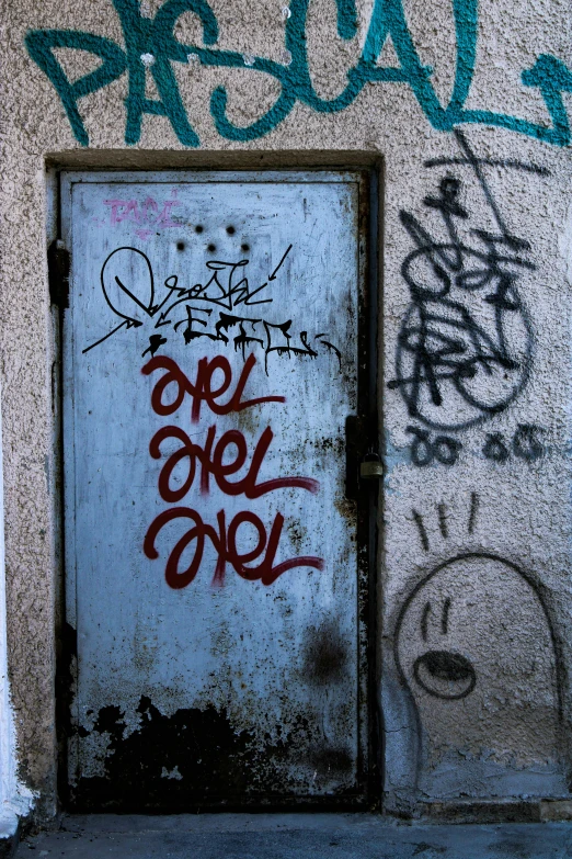 graffiti on the side of a door in front of a cement wall