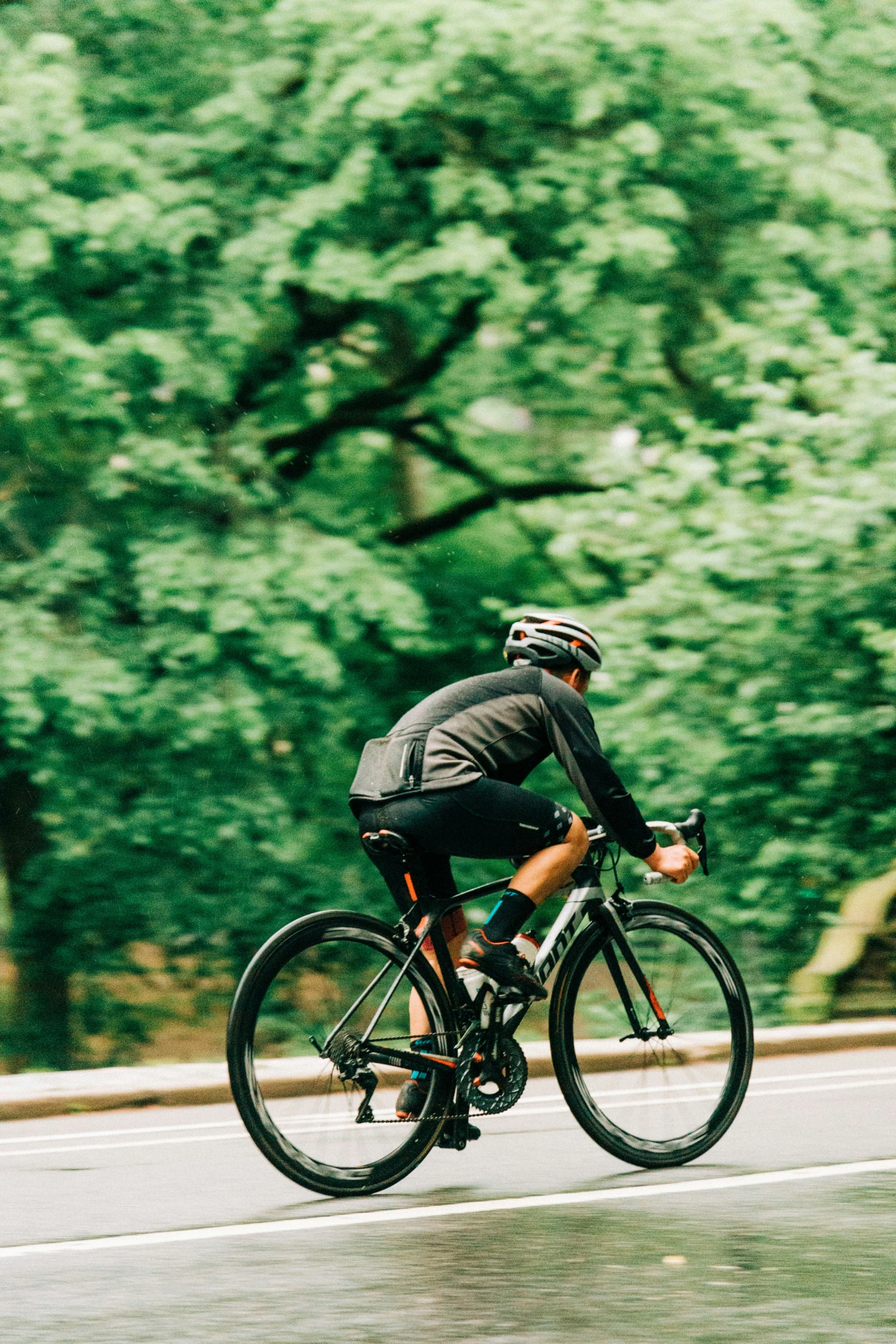 a man wearing a helmet and riding his bike down a rain soaked road