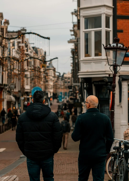 two men standing side by side in front of a building