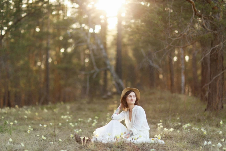 a woman in the woods is sitting on the ground