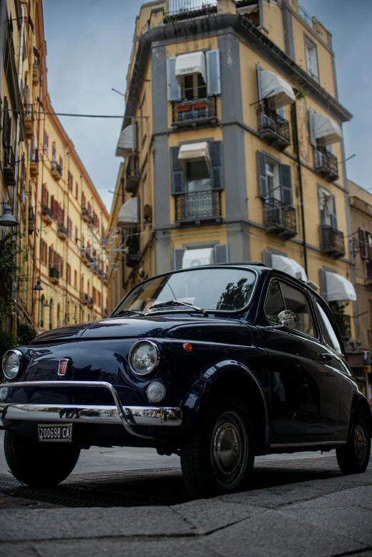 an old fashioned car is sitting outside of a tall building