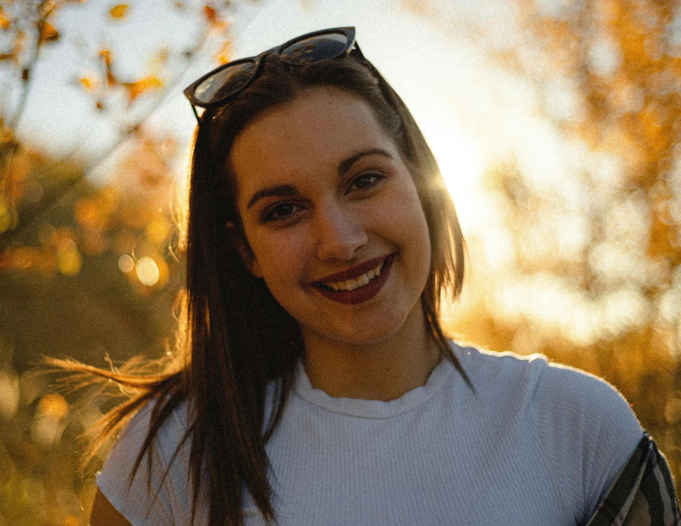 a woman wearing sunglasses and white shirt in the sun