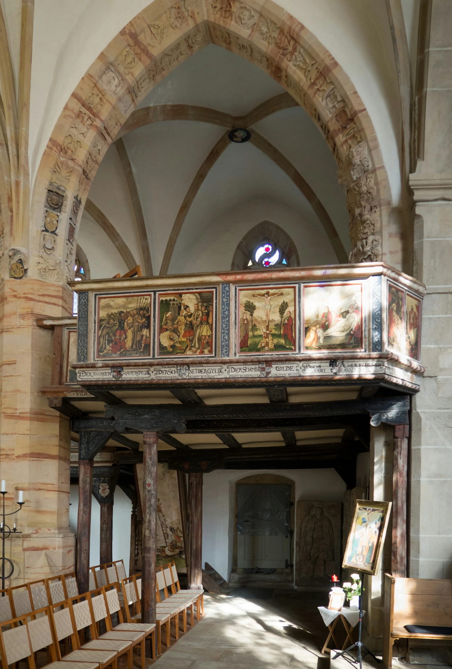 an empty church with many chairs, a painting on the wall and a painting hanger above the pews