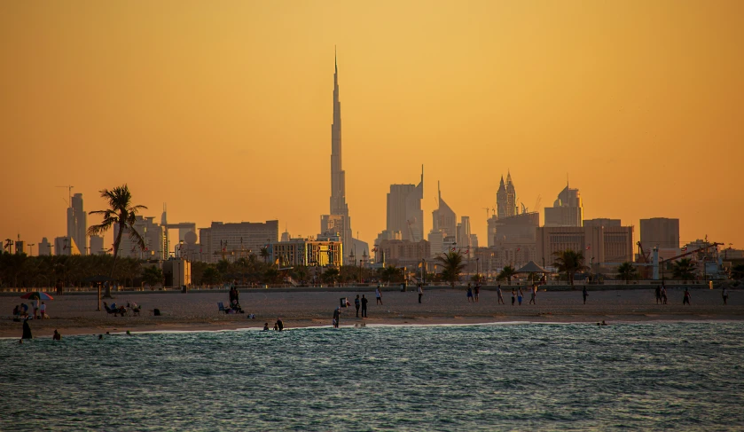 a city with tall buildings and some people on the beach