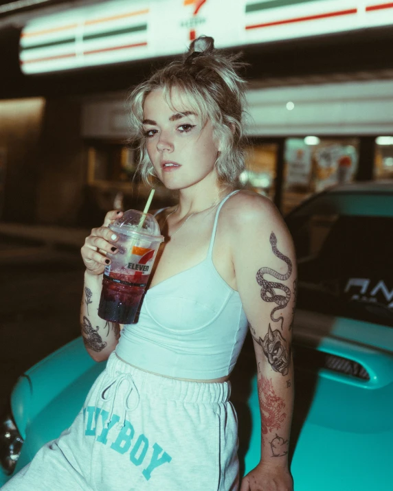 a tattooed girl holding up a drink