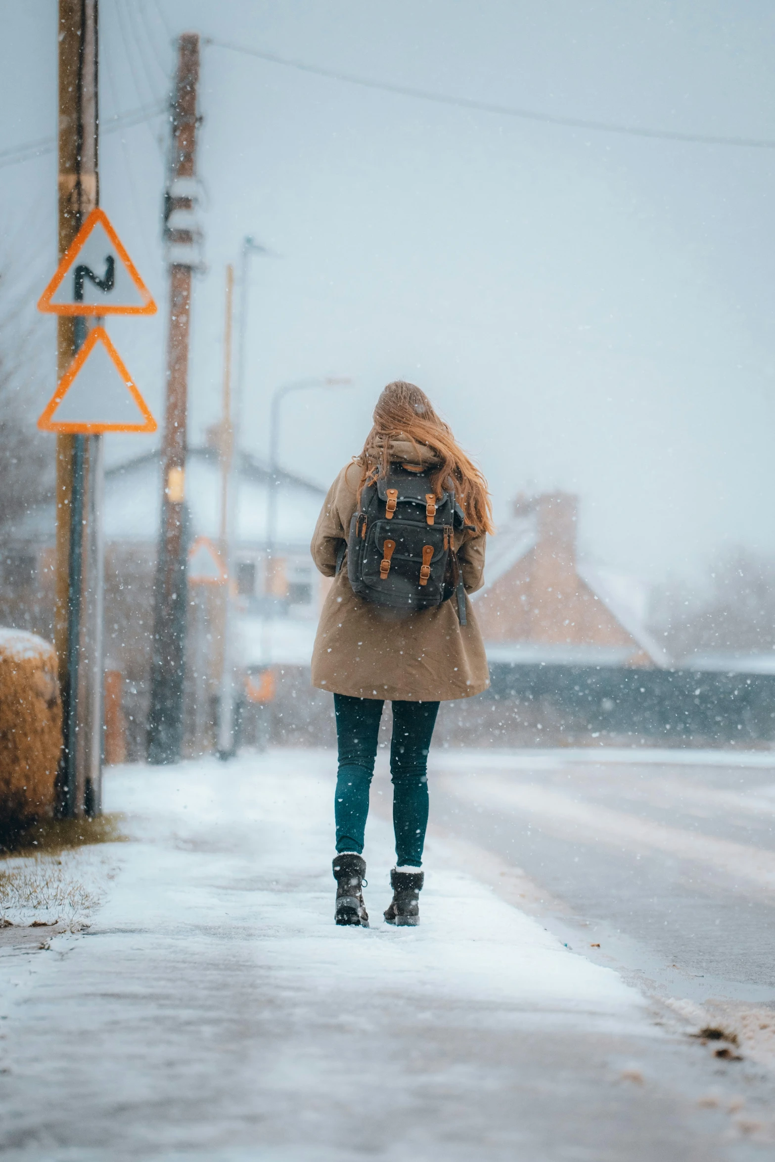 a person on a road in the snow with backpack and boots