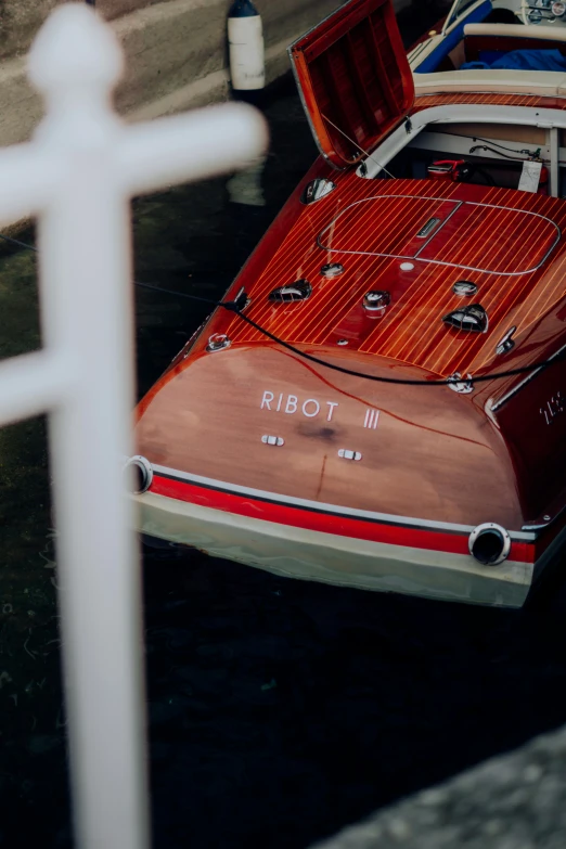 the boat is red and white and has wooden trim