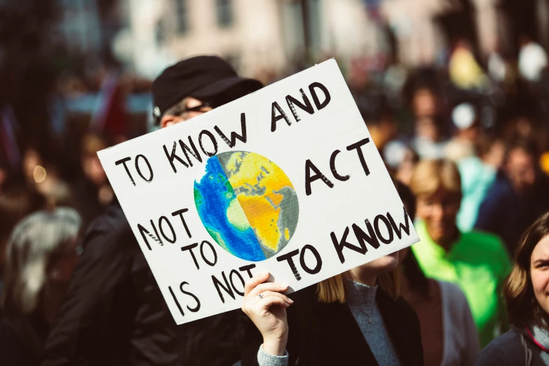 people holding signs that read to know and not to act is not to know