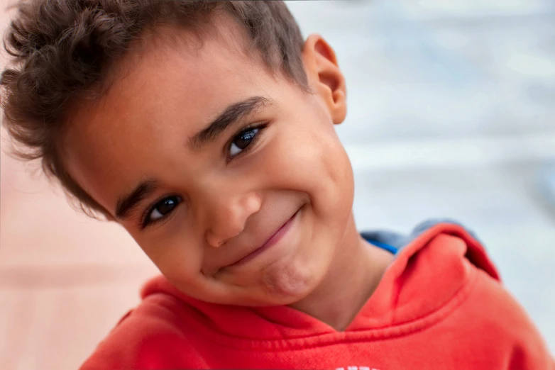 this little  is smiling while wearing a sweatshirt