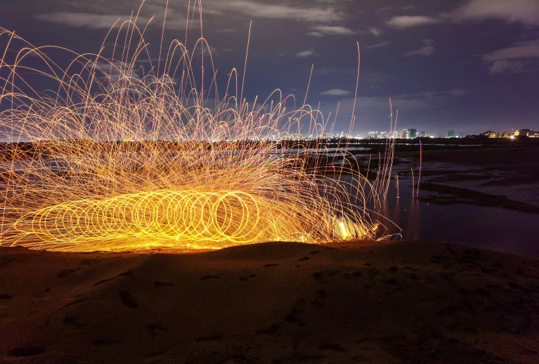 some fireworks and sparks on a beach during the night