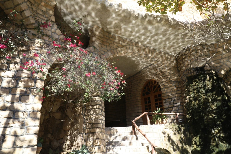 a stone building with plants growing on the side and stairs