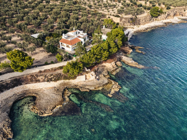 a large home on a cliff next to the ocean