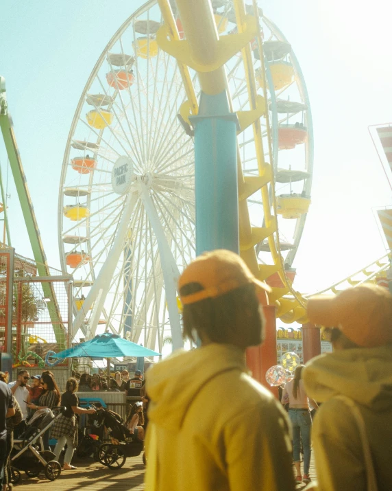 two people in yellow jackets stand in front of a ferris wheel