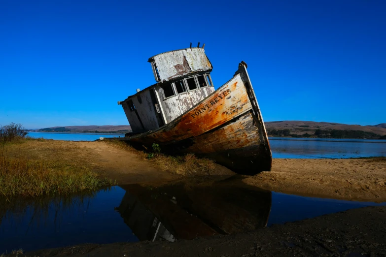 a boat is sitting on a beach next to the water