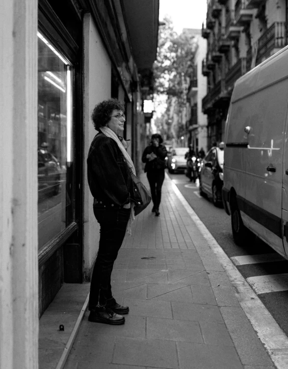 a black and white po of a woman standing next to the side of a building