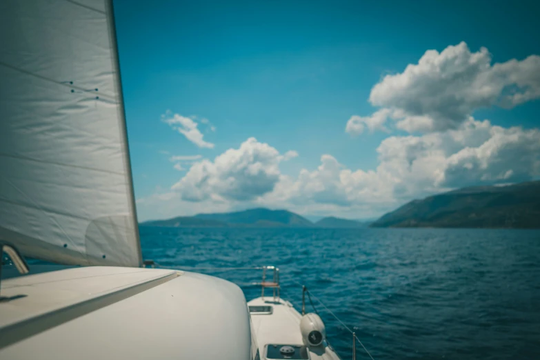 a sailboat with blue skies and clouds in the background