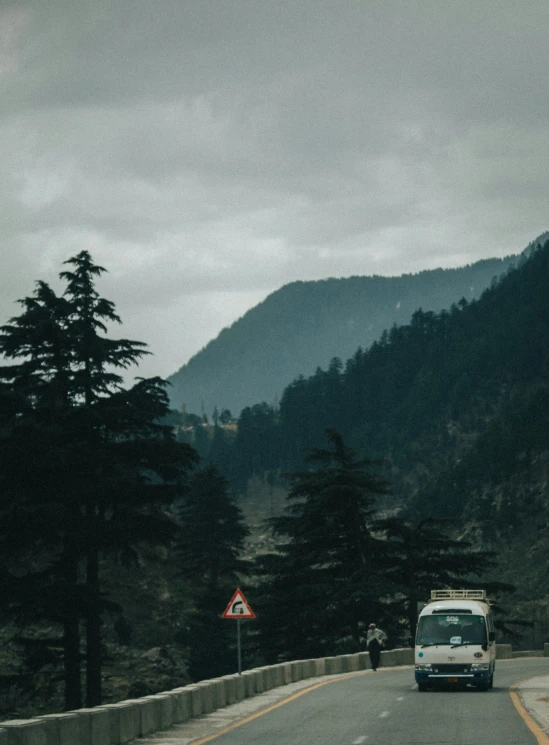 a white bus traveling along the road under clouds