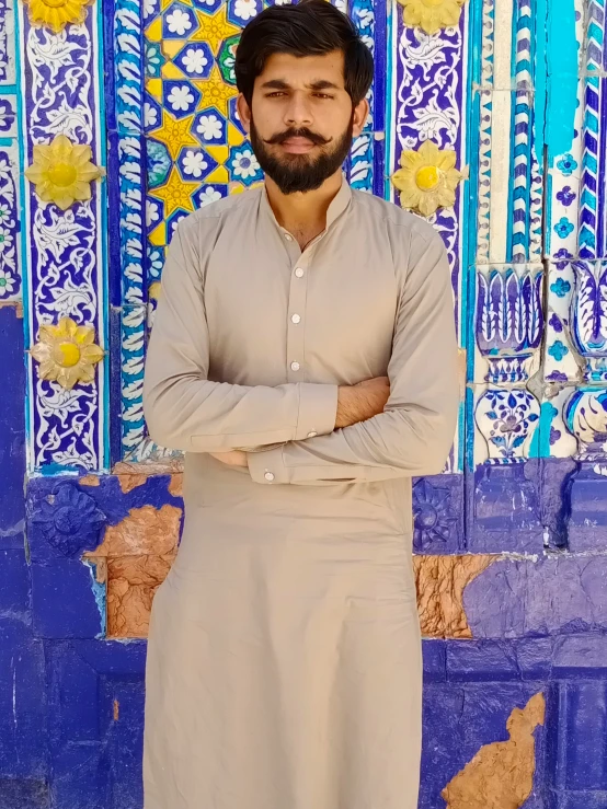 man standing with arms crossed on ornately painted background