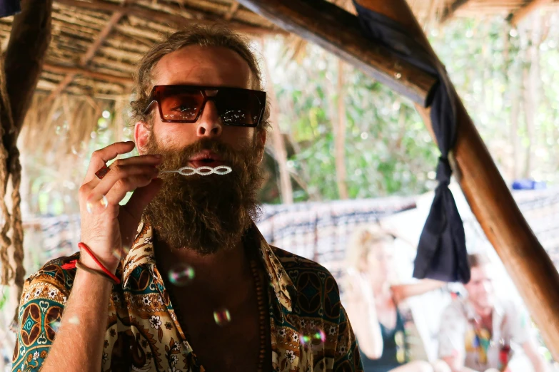 a man with a long beard and sunglasses smoking
