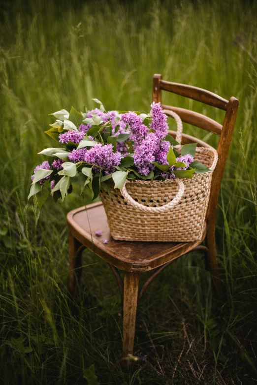 a woven wicker basket with purple flowers in it sits on an old chair