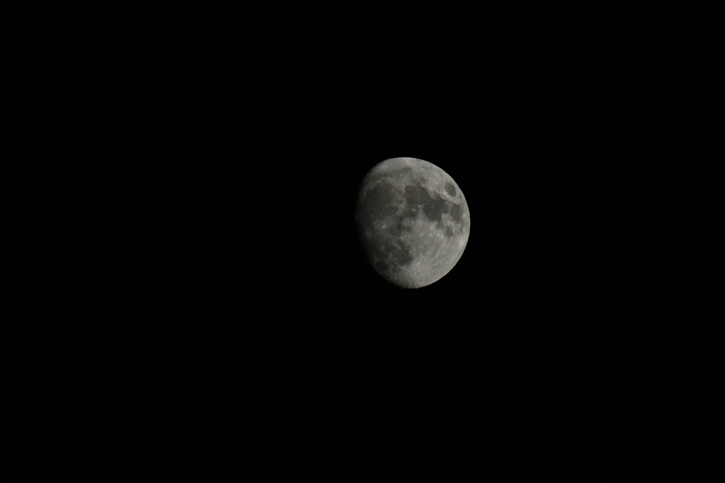 a moon lit up in the dark sky with no clouds