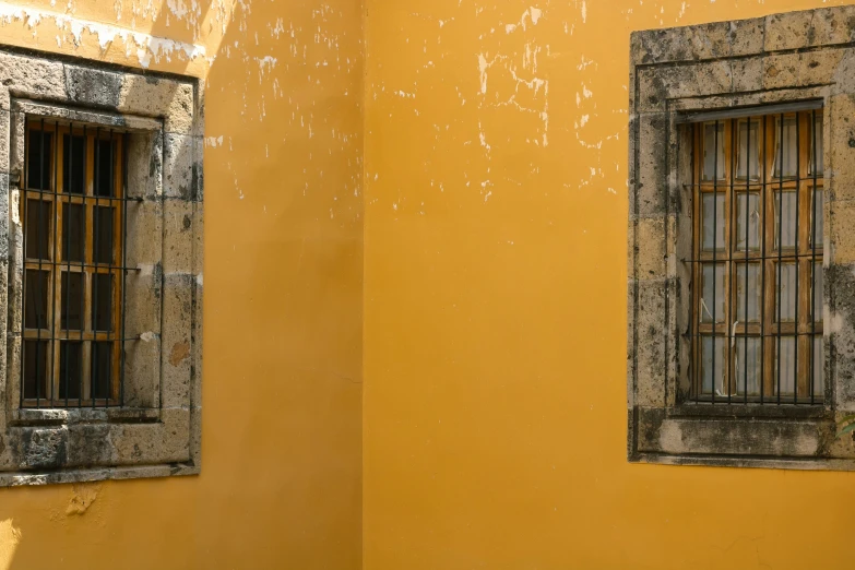 two windows next to each other on a yellow wall