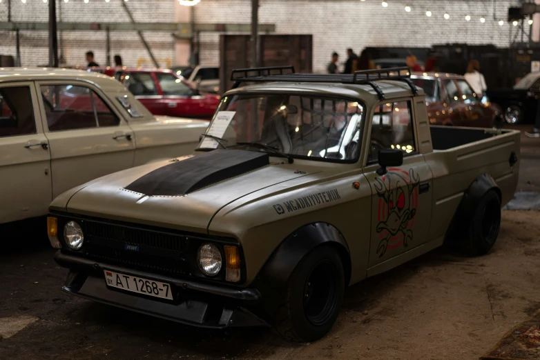 a green truck with painted stickers and a white car