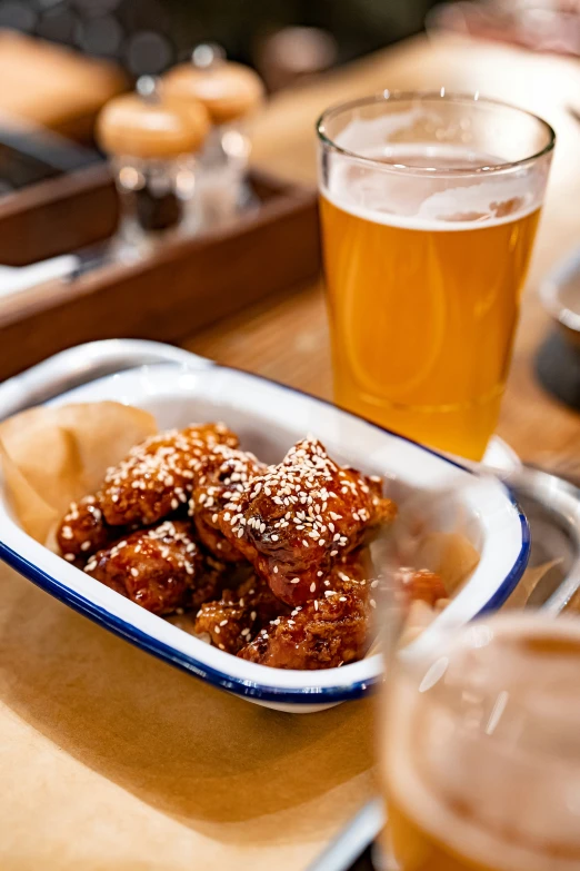 a plate with some chicken and beer on a table