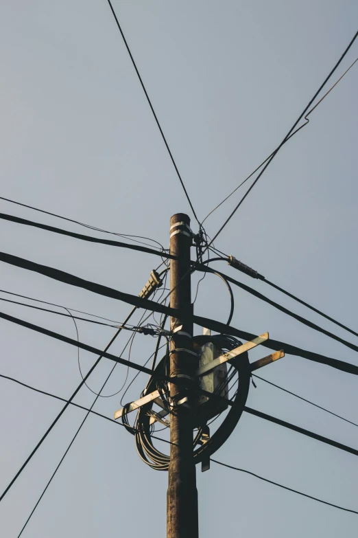 multiple electric wires hanging from wooden poles and in blue sky